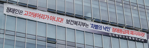 전국장애인차별철폐연대는 지난 9월 13일 장애등급심사 중단 등을 요구하며 국민연금공단 장애심사센터를 점거했다. 장애심사센터 건물에 장애등급제 폐지를 요구하는 플랜카드가 걸려 있는 모습. ⓒ에이블뉴스 