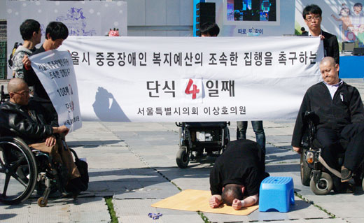 서울시 중증장애인 복지예산 집행 촉구를 위한 공동투쟁연대가 응원하는 가운데 이상호 서울시의원이 108배를 진행하고 있는 모습. 이상호 의원 옆에는 삭발식을 거행한 서울장애인자립생활센터 박찬오 소장(좌)과 새날동대문장애인자립생활센터 구근호 소장이 자리하고 있다. ⓒ에이블뉴스