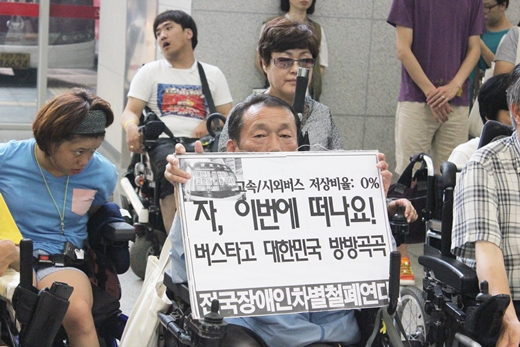 31일 열린 기자회견에서 한 장애인이 ‘자! 떠나요 버스타고 대한민국 방방곡곡’이 적힌 피켓을 들고 있다. ⓒ에이블뉴스