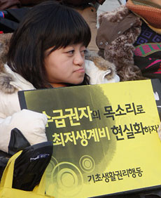 기자회견에 참석한 한 활동가가 '수급권자의 목소리로 최저생계비 현실화하자'라는 플랜카드를 들고 있다. ⓒ에이블뉴스 