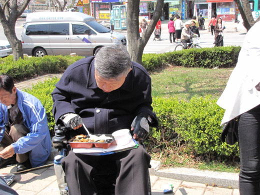 휠에어장애인들이 식탁이 부족해 외부로 나와 도시락을 무릎에 놓고 식사하고 있다. ⓒ박종태 