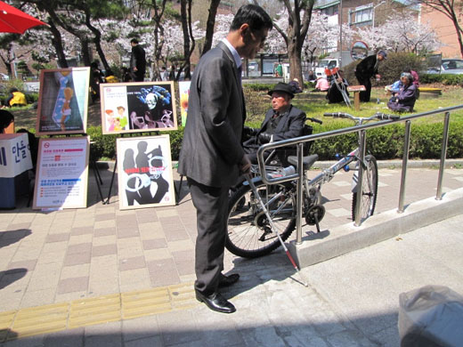 주차장으로 가는 경사로 손잡이와 그 앞의 점자유도블록이 일직선으로 설치돼 있어 시각장애인이 부딪치기도 했다. 시각장애인이 항의하고 있는 장면. ⓒ박종태