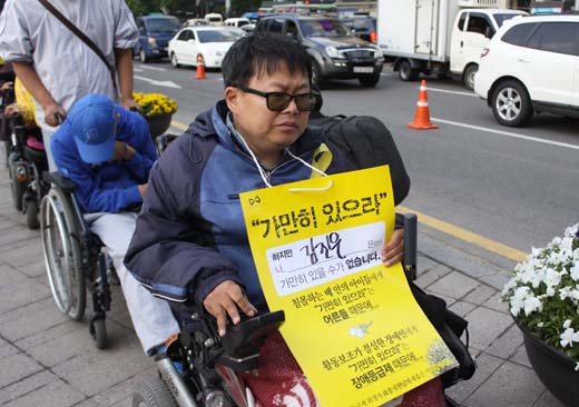 故송국현씨를 추모하는 노란리본과 "가만히 있으라"고 적힌 포스터를 매단 장애인이 거리로 이동하고 있다. ⓒ에이블뉴스